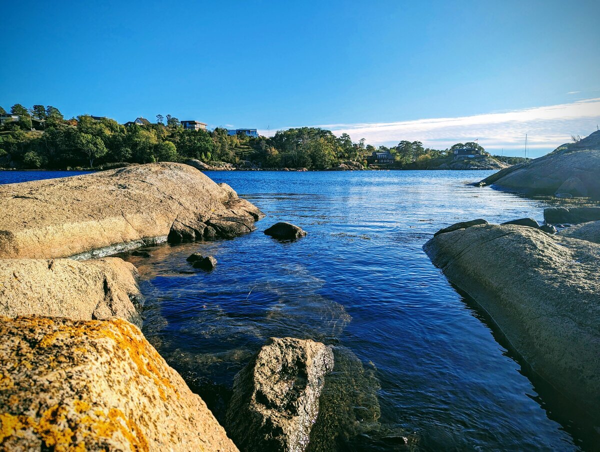 Naturskjønn kystlinje med steiner og klart vann